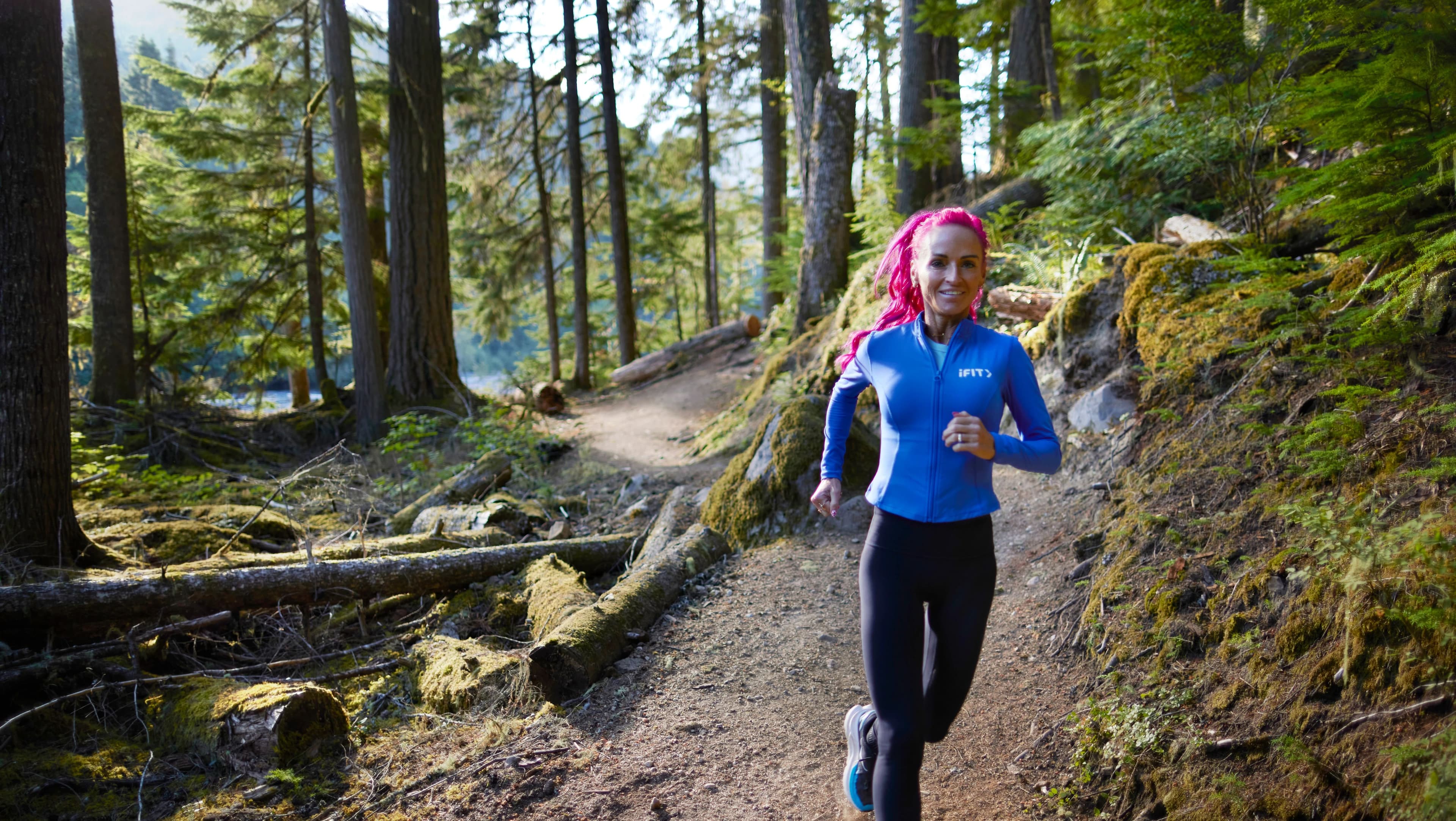 iFIT Trainer Ashley Paulson runs a forested trail while training for an ultramarathon, part of the race day planning covered in this guide.
